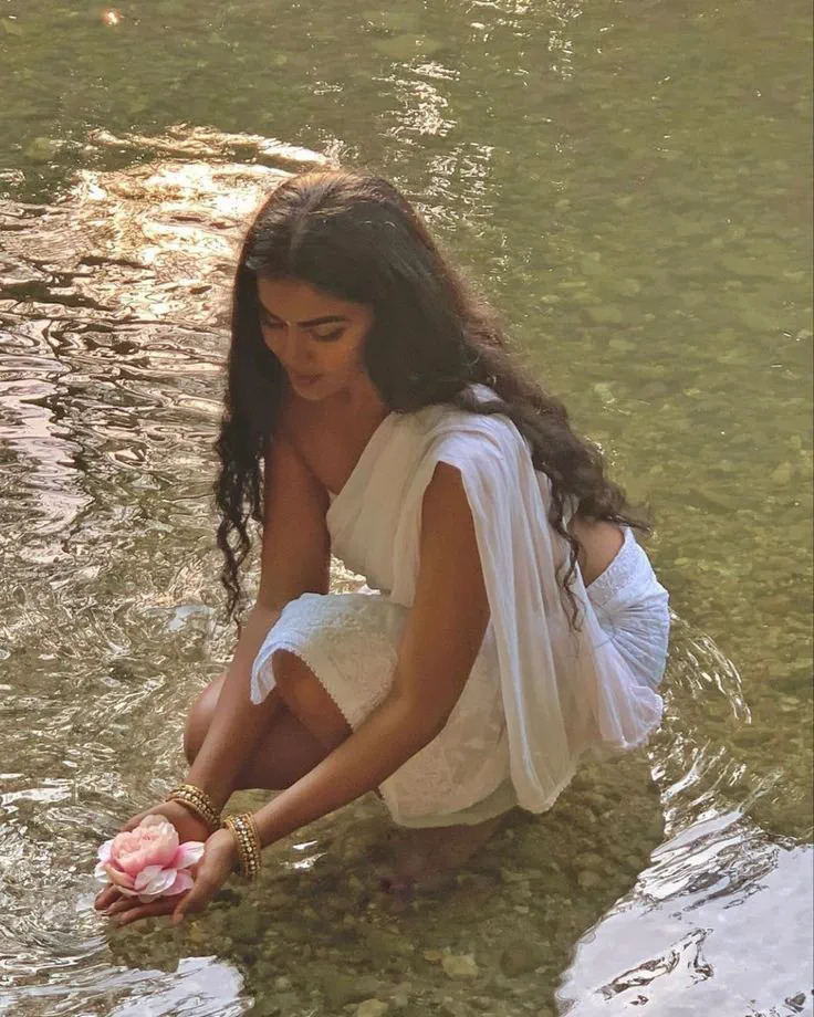 A woman in linen standing peacefully in a sunlit meadow